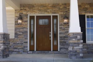 A custom front door surrounded by stone siding.