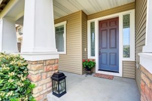 A beautiful home entryway with decorative columns and a brown entry door.