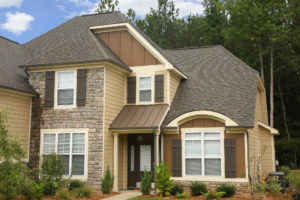 A beautiful home with brown roof shingles and light brown siding.