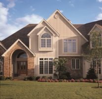 Big suburban home with a front yard, arches entryway, and insulated vinyl siding 