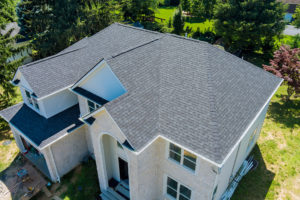 Aerial view of a light gray, asphalt shingle roof on a two-story home